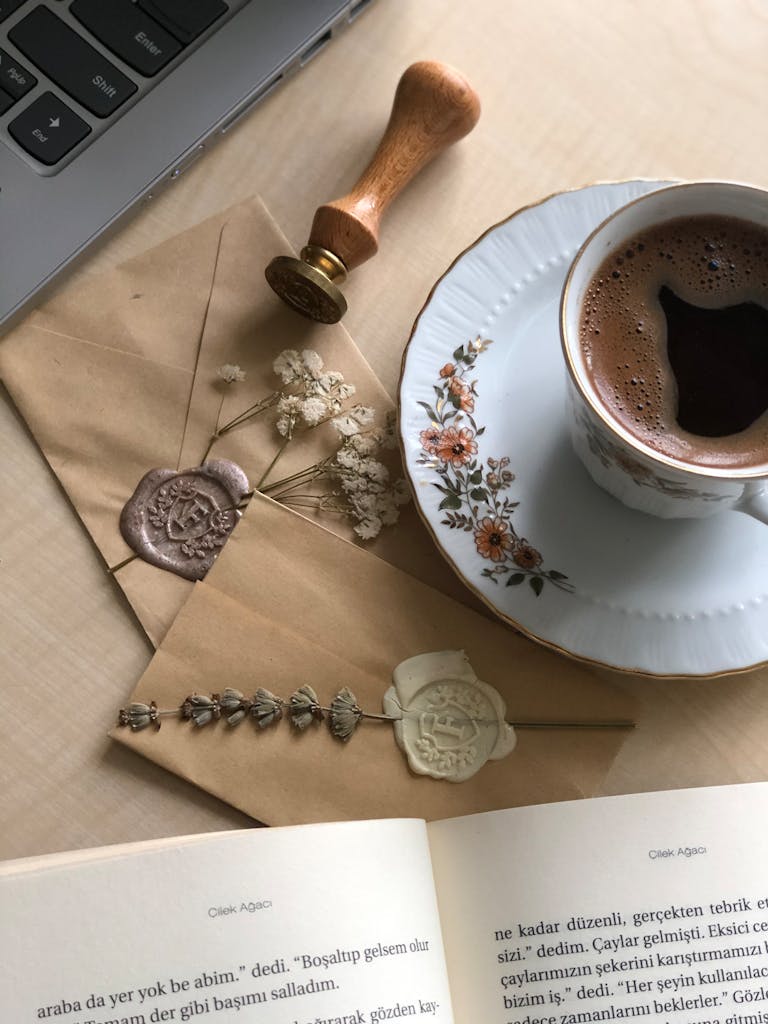 Elegant vintage coffee setup with sealed envelopes and open book, offering a cozy, warm ambiance.