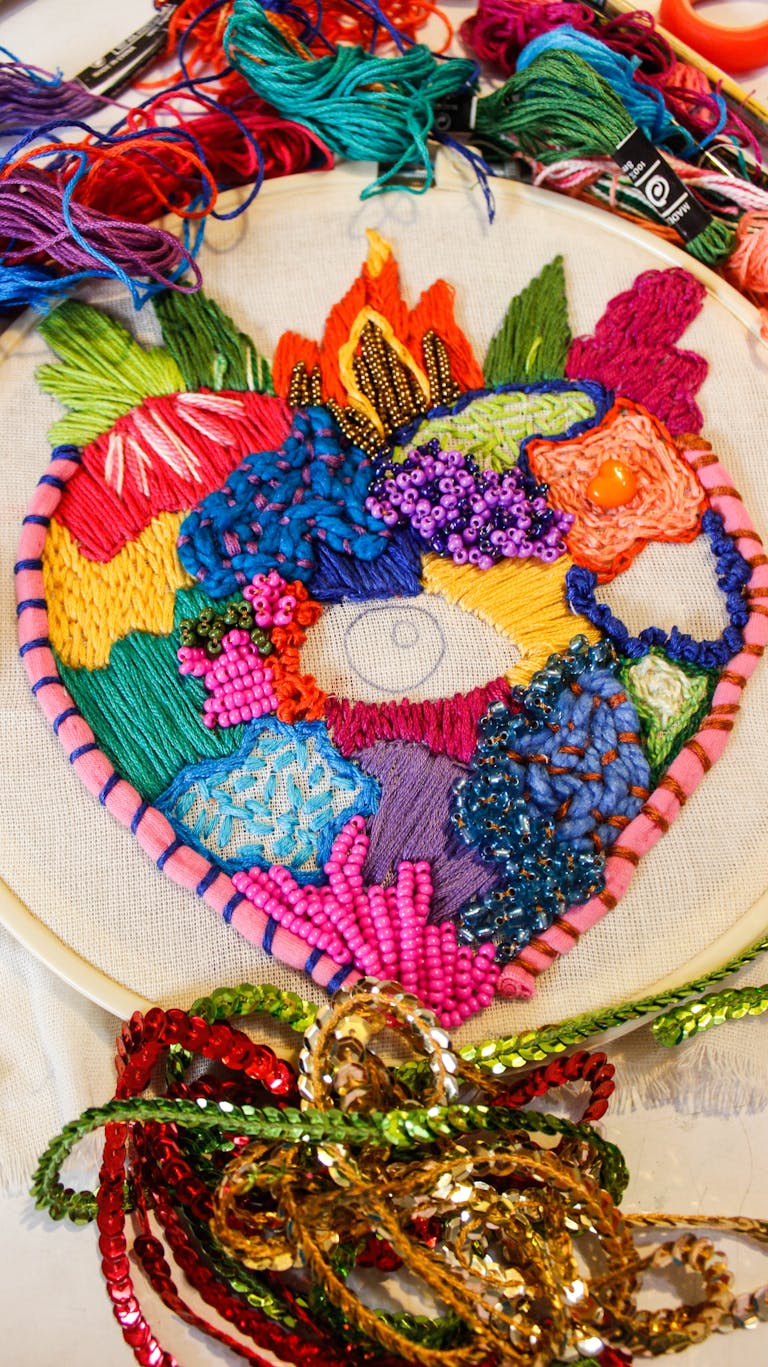 Vivid handmade embroidery heart with colorful threads and beads.